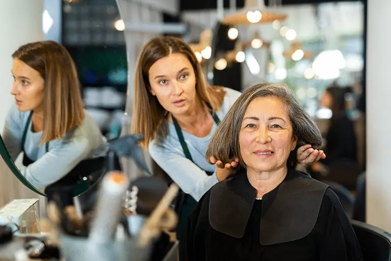 Senior salon care technician styling a seniors hair